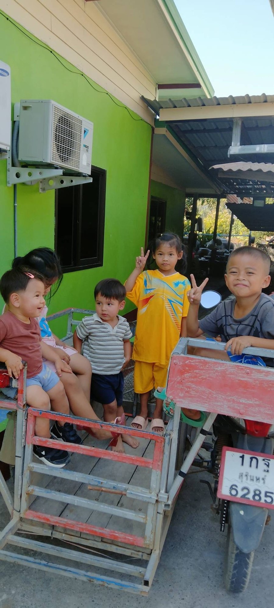 Neighborhood children in Thailand riding on a cart, greeting Benjamin Cunningham's family