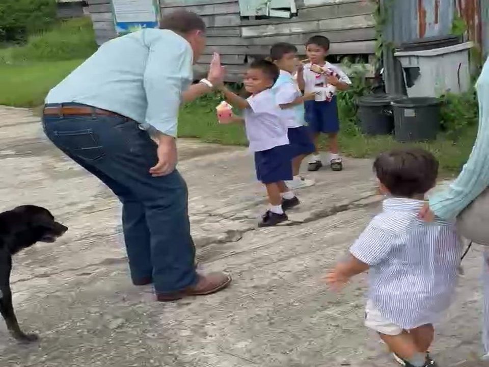 Benjamin Cunningham greeting young schoolchildren outside a village school